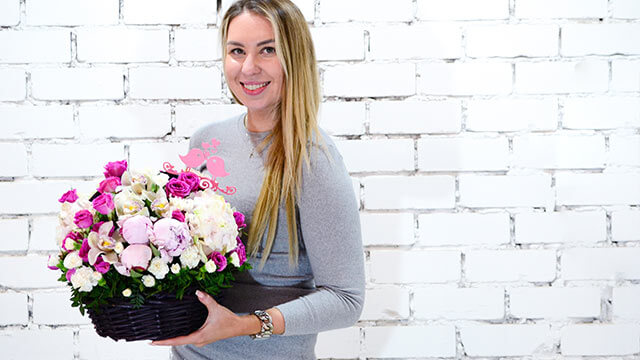 Smiling woman holding a basket of flowers