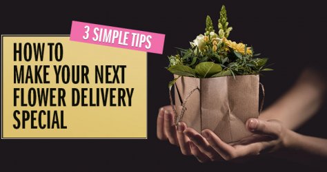 Hands holding a flower arrangement in a paper gift bag.
